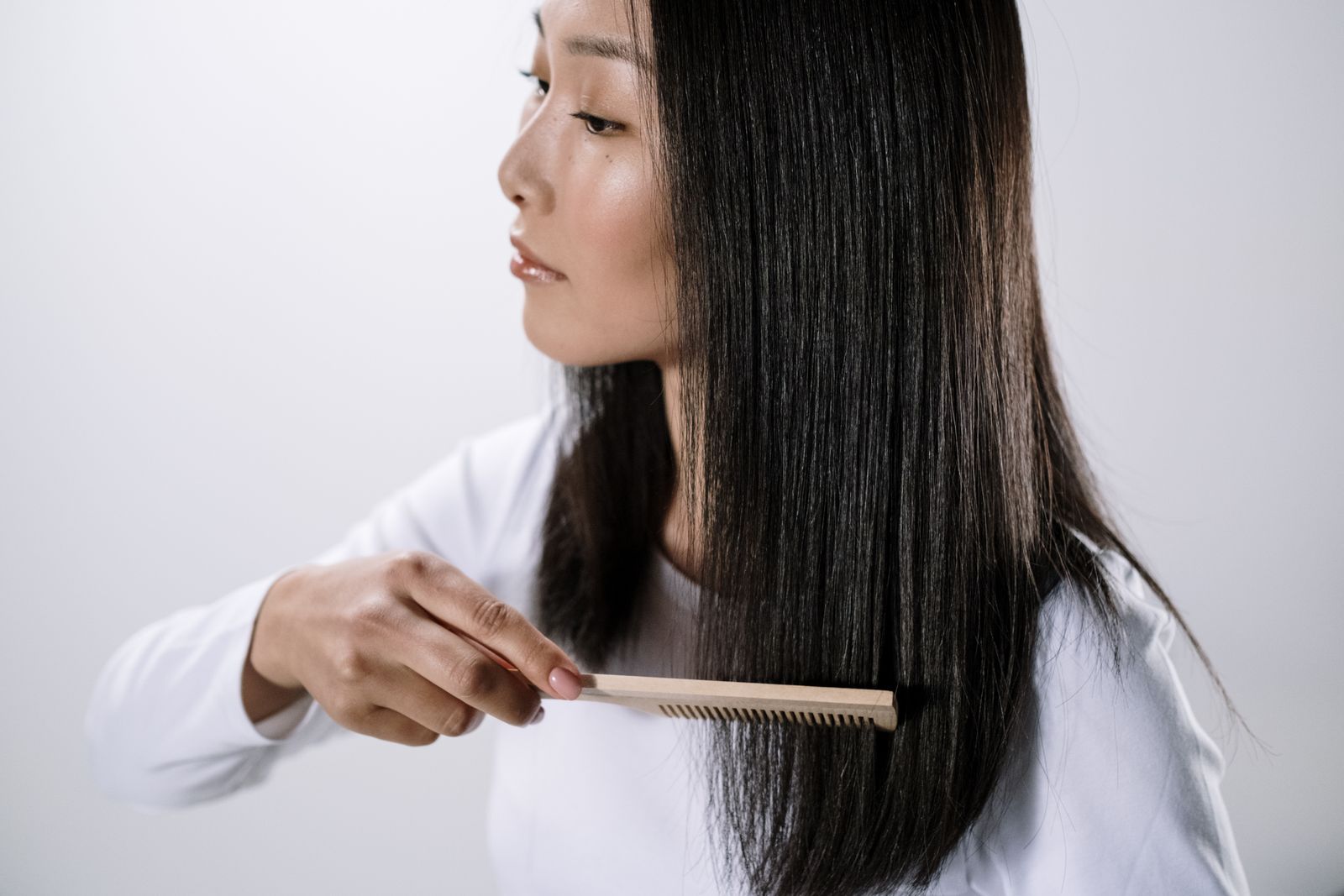秋季掉髮完整指南 2026 封面：女性以木梳梳理柔順黑髮、光線明亮乾淨，對應季節性落髮的日常頭皮照護意象